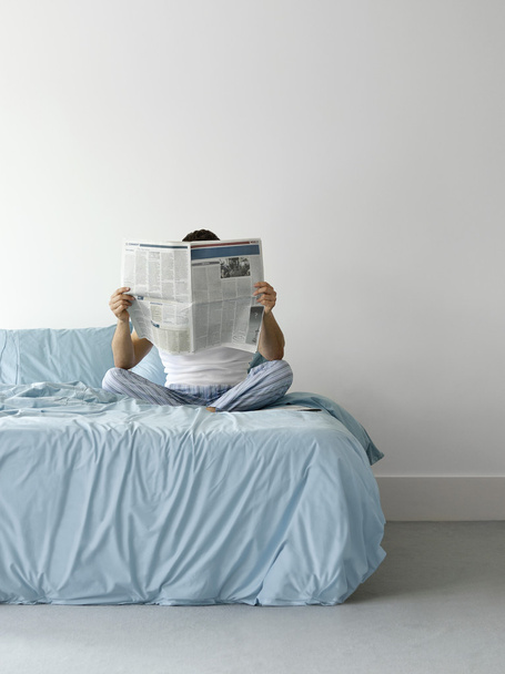 Man on bed reading newspaper - Photo, image