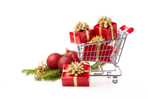 Shopping trolley with gift boxes and brenches of fir-tree with decoration on a white background. Christmas and New Year sale. - Photo, image