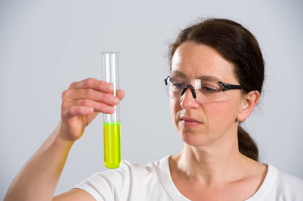 dark haired female lab assistand with test tube - 写真・画像