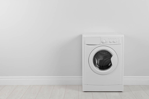 Modern washing machine near white wall, space for text. Laundry  - Fotografie, Obrázek