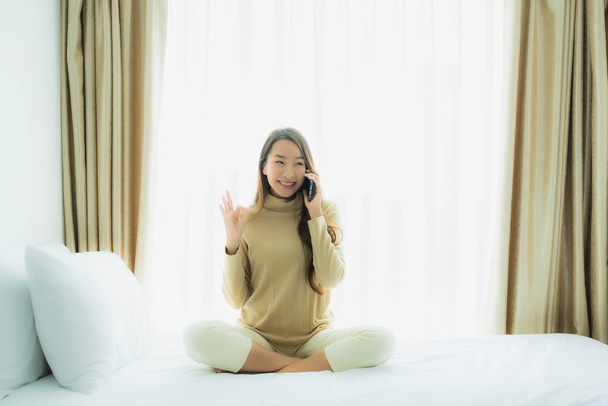 Young asian woman using mobile smart phone on bed - Foto, imagen