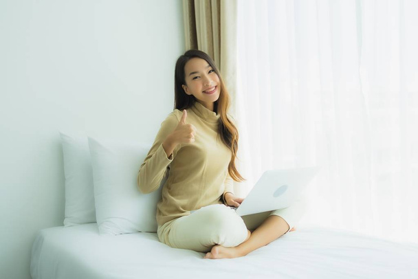 Joven mujer asiática utilizando ordenador portátil en la cama
 - Foto, Imagen