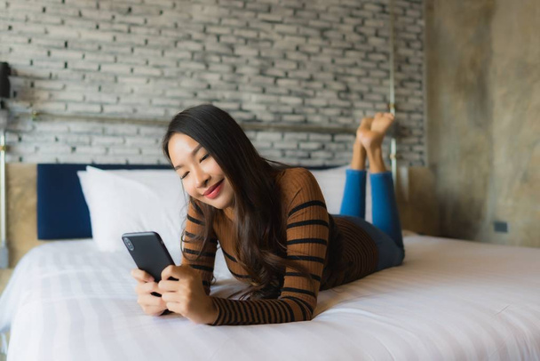 Young asian woman using mobile smart phone on bed - Photo, Image