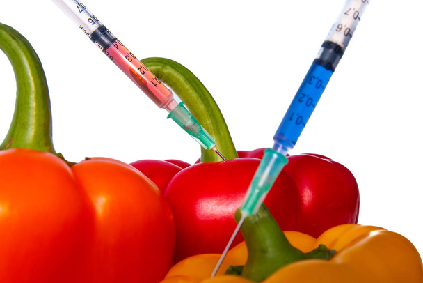 Genetically modified vegetables. GMO food concept. Syringes are stuck in vegetables with chemical additives. Injections into fruits and vegetables. Isolated on white background.  - Photo, Image