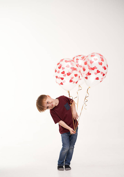Sweet boy holding balloons with red and pink hearts. Valentines day or kids healthcare, medical concept - Zdjęcie, obraz