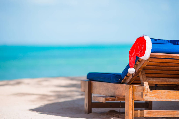 Tumbonas con Sombrero de Santa en la hermosa playa tropical con arena blanca y agua turquesa. Vacaciones perfectas de Navidad
 - Foto, imagen
