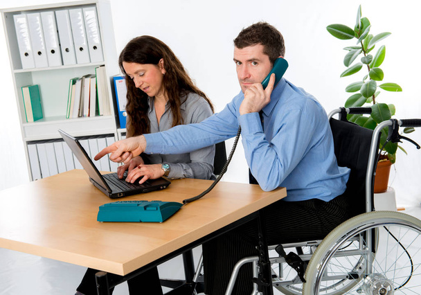 Tekerlekli sandalyedeki engelli iş adamı ve bayan meslektaşı - Fotoğraf, Görsel
