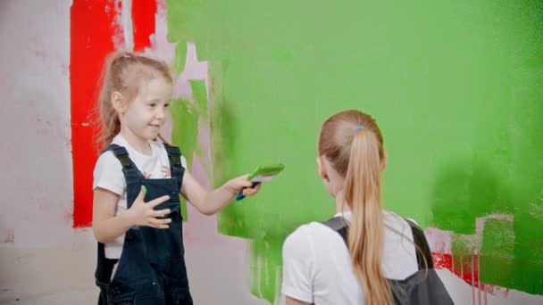 Mom and daughter are playing with a brush and a roller and smearing with paint - Video, Çekim