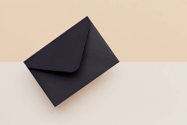 Black envelope on the biege double colored background. Mail concept - Photo, Image