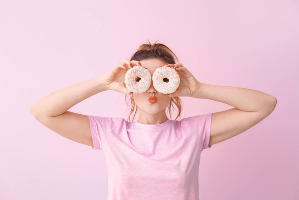 Funny young woman with donuts on color background - Photo, Image