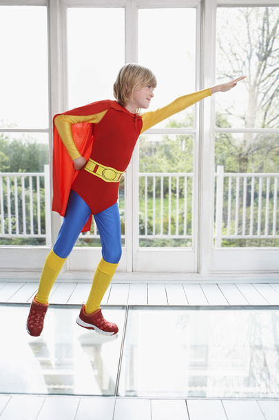 Boy wearing superhero costume with arm extended - Zdjęcie, obraz