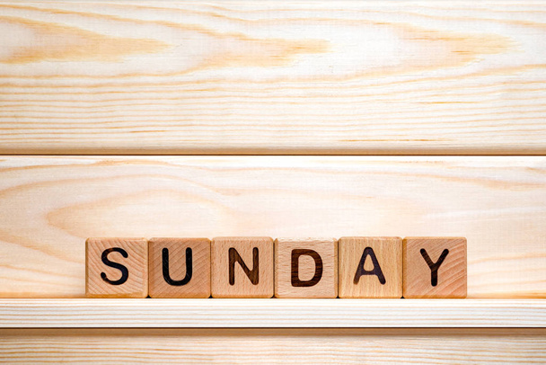 Sunday word written with vintage wooden cubes on wooden background. Day off background. Business concept. Small business. The word Sunday on wooden cubes. Weekday business concept. - Valokuva, kuva