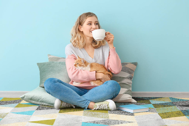 Beautiful young woman with cute cat drinking tea at home - Fotografie, Obrázek