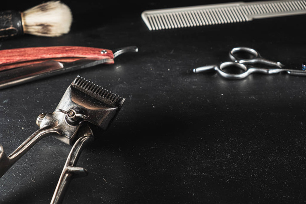 Vintage-Friseurausrüstung auf schwarzem Hintergrund. professionelle Friseurwerkzeuge. Schere, Handhaarschneider, Rasiermesser, Rasierpinsel, Kamm. Kopierraum - Foto, Bild