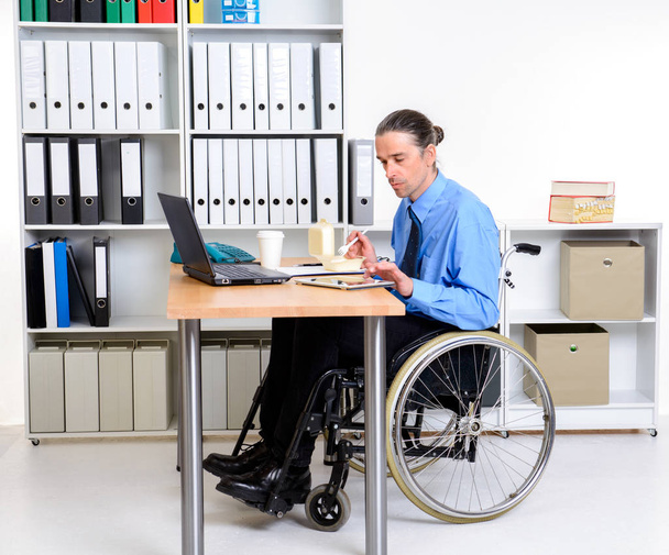 disabled business man in wheelchair eating in the office - Foto, imagen