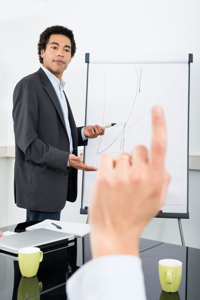 Businessman Explaining Graph With Colleague Raising Hand - Foto, Bild
