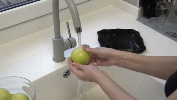 A woman washes green apples in the kitchen sink. Homework. Healthy diet. Closeup. 4k. - Video
