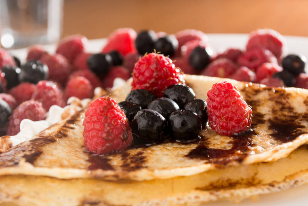 Fresh pancakes with fruit arranged all over it, and with cream - Фото, зображення