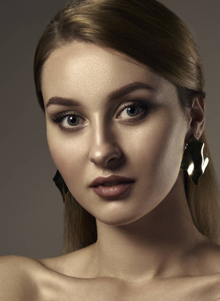 Vertical head shot of red head girl with perfect fresh skin wearing wavy gold earrings - Zdjęcie, obraz