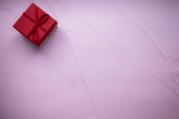 Red gift box in the corner on a pink background. Place for text. - Foto, Bild