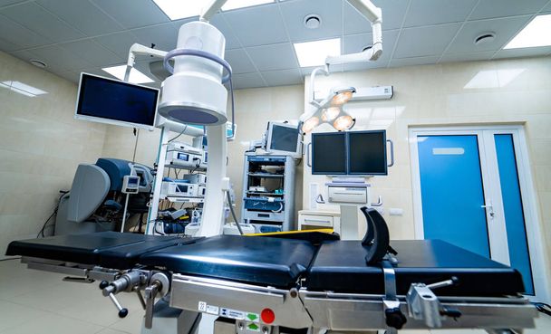 Establishing shot of technologically advanced operating room with no people, ready for surgery. Operating theater with working equipment, lights and computers ready for surgeons. - 写真・画像