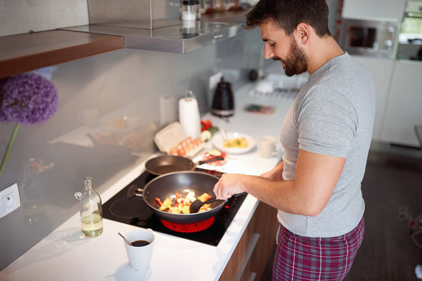 Guy in pajamas prepare breakfast at home. - Фото, изображение