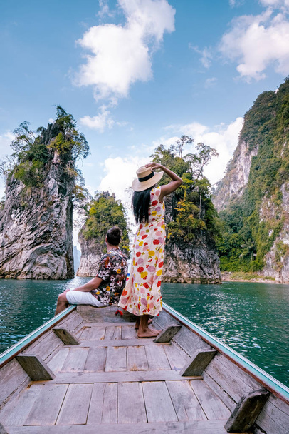 coppia che viaggia in barca esplorando scogliere calcaree epiche in enorme lago nel Khao Sok National Park, lago Chiew lan, Thailandia
 - Foto, immagini