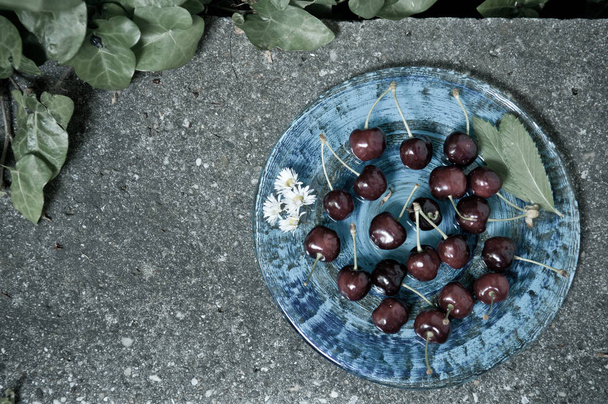 Delicious ripe cherry  on blue plate on grey stone flat lay Healthy fruit eating Top view - Foto, immagini