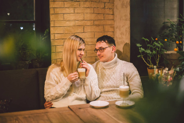 Ευτυχισμένο ζευγάρι και πίνοντας καφέ. αγάπη και ρομαντική ημερομηνία στο κέντρο της πόλης καφέ εστιατόριο. Νεαρό ευτυχισμένο ζευγάρι ερωτευμένο στο καφέ. Νεαρό ζευγάρι ημερομηνία στο καφέ, μιλάμε και φιλιά την εποχή των Χριστουγέννων - Φωτογραφία, εικόνα