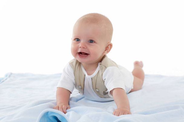 Happy little baby boy is lying on his stomach  on a plaid on a white background. Six month. - Photo, image