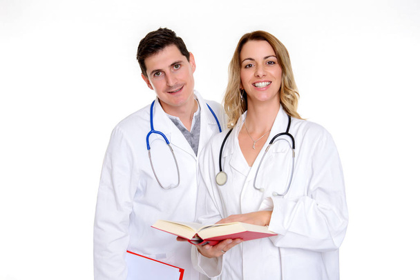 young friendly medical team with book in lab coat in front of white background - Fotó, kép