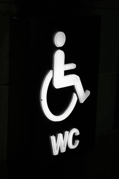 Señal de inodoro para discapacitados de cerca. Fotografiado en ángulo. Con colores blanco y negro. De cerca.
 - Foto, imagen