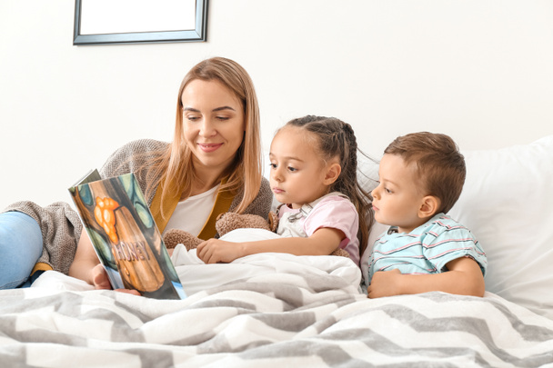 Kindermädchen liest Gute-Nacht-Geschichte für süße kleine Kinder - Foto, Bild