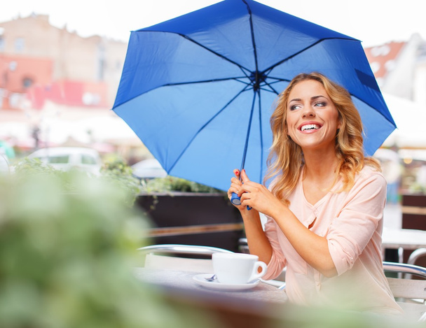 Girl with blue umbrella sitting in summer cafe - Valokuva, kuva