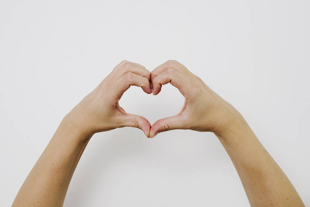 Hart gemaakt van handen. Concept van liefde, respect en steun. Handen op een hartteken op een helderwitte achtergrond. Zoek naar steun en liefde. - Foto, afbeelding