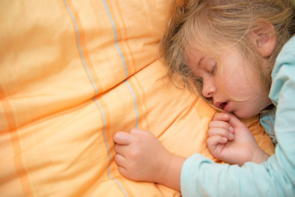 little girl is sleeping on orange pillow - Фото, зображення