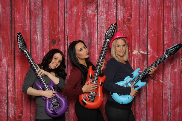 three young women are playing on plastic guitars - 写真・画像