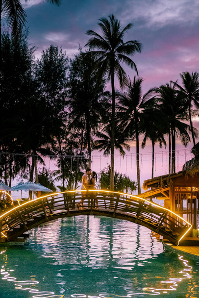 paar kijken zonsondergang bij het strand en het zwembad van een luxe resort in Thailand Khao Lak - Foto, afbeelding
