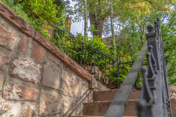 Close up of outdoor stairs with black metal handrail against a stone wall - Photo, Image