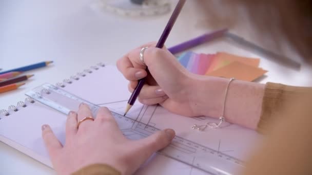 Handheld over the shoulder shot of a designer using a ruler to sketch out a design - Filmati, video