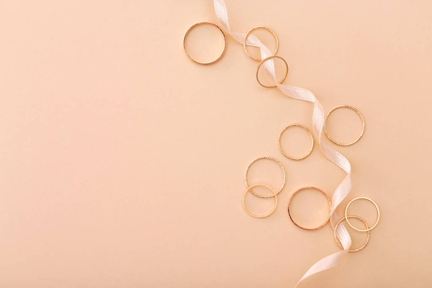 Many golden rings and ribbon on beige background - Foto, immagini