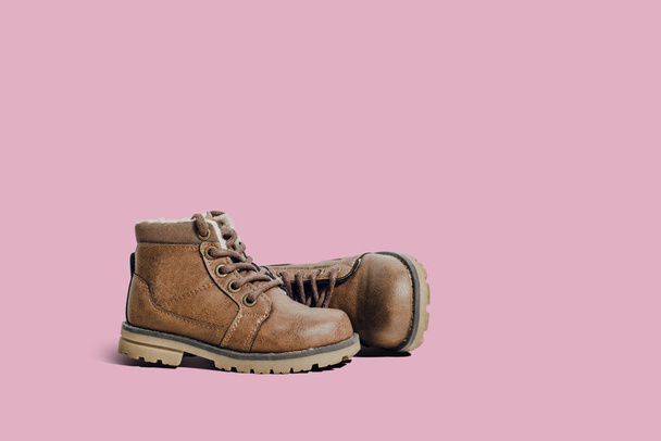 A pair of leather, children's shoes on a pink pastel background. The concept of upcoming cold, selling shoes. A warm, comfortable shoe for children with fur. - 写真・画像