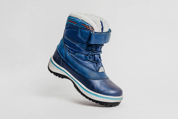 Blue children 's shoe on a pastel, gray background. Концепция предстоящего холода, продажи обуви. Теплая, удобная обувь для детей с мехом под углом и наклоном
. - Фото, изображение