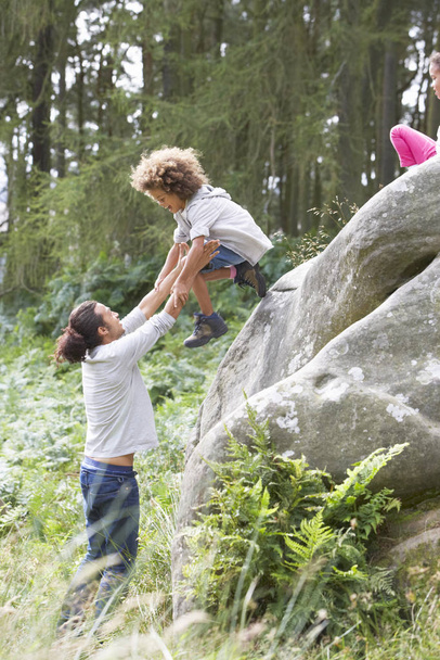 Father Helping Children To Jump Off Rocks - Fotó, kép