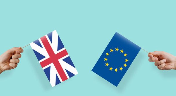 Iso-Britannia ja Euroopan unioni pitävät lippuja käsissään. Käsi nostaa EU:n ja Ison-Britannian lipun. Valtioiden välisten suhteiden käsite, talousyhteisö, politiikka. BREXIT
. - Valokuva, kuva