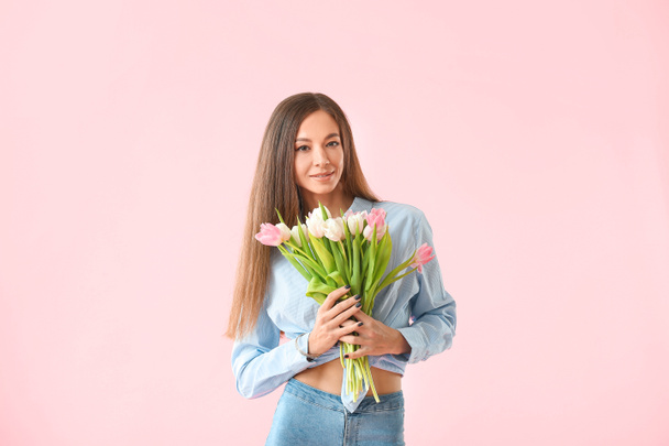 Krásná mladá žena s květinami na barevném pozadí. Mezinárodní oslava Dne žen - Fotografie, Obrázek