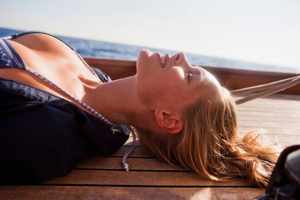 woman lying on deck eyes closed - Φωτογραφία, εικόνα