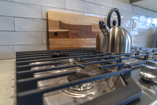Cookpot with kettle against wooden chopping board and tile backsplash - Photo, Image