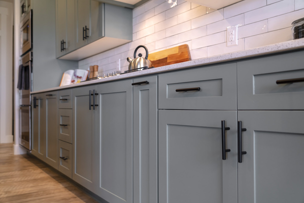 Küchenschränke mit weißer Arbeitsplatte, schwarzen Griffen und Fliesen-Backsplash - Foto, Bild