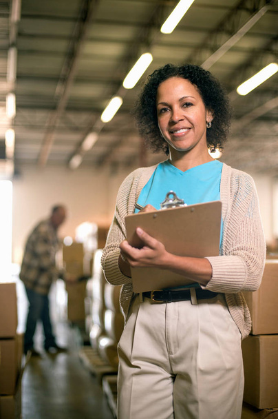 Portrait of female warehouse worker holding clipboard - 写真・画像